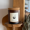 candle labeled "smokey sage" on a shelf with a plant